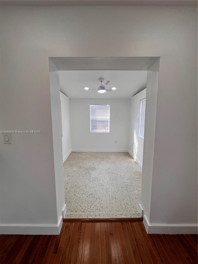 unfurnished room with ceiling fan, baseboards, and wood finished floors