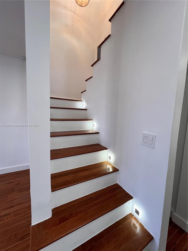 staircase with baseboards and wood finished floors