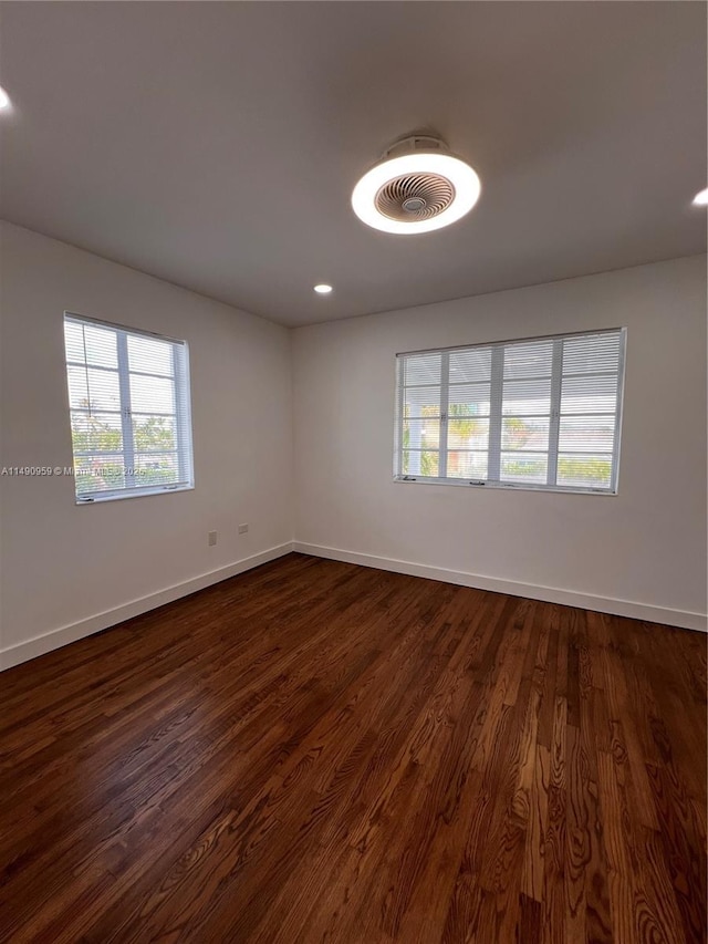 empty room featuring recessed lighting, dark wood finished floors, and baseboards