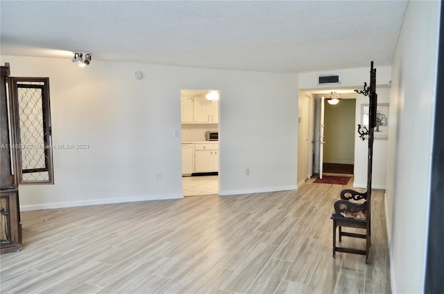 spare room featuring a textured ceiling and light wood-type flooring