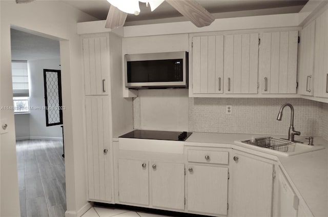 kitchen featuring white cabinetry, ceiling fan, sink, light wood-type flooring, and tasteful backsplash