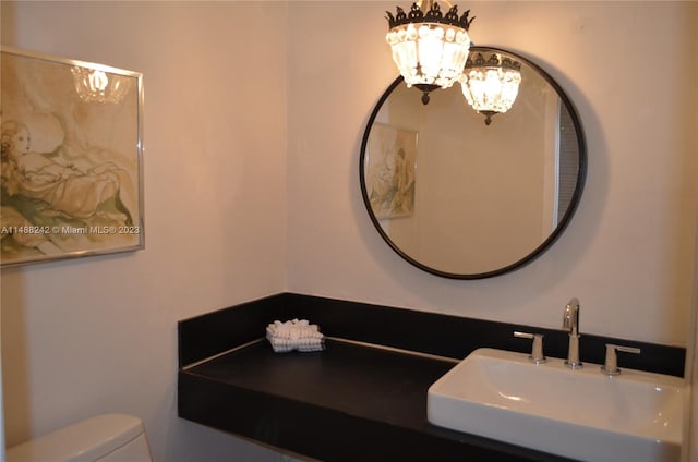 bathroom featuring toilet, an inviting chandelier, and sink