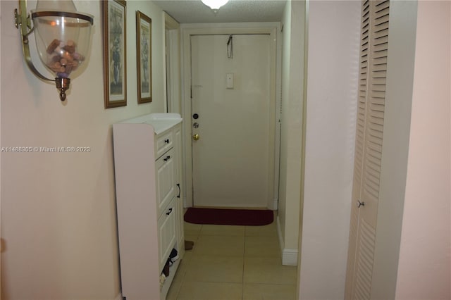 hall featuring light tile floors and a textured ceiling