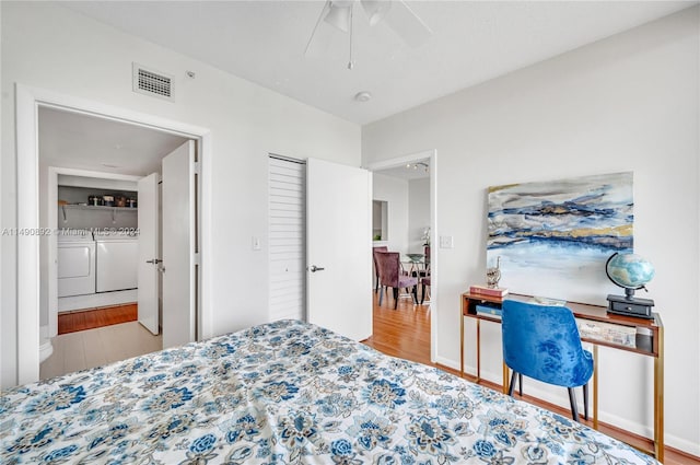 bedroom featuring built in desk, ensuite bathroom, ceiling fan, hardwood / wood-style floors, and washer and dryer