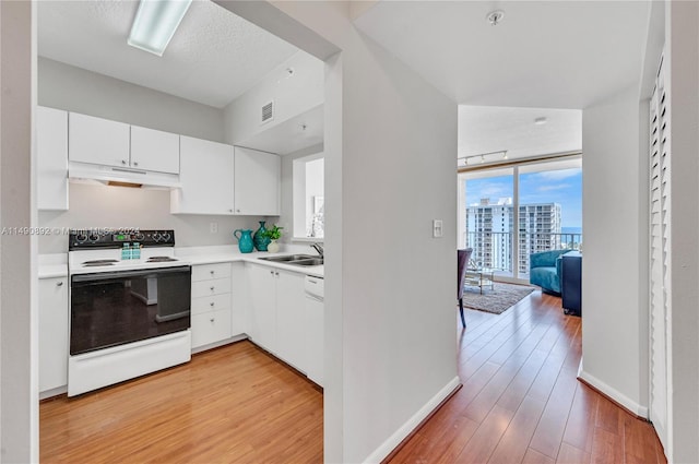 kitchen featuring white range with electric cooktop, white cabinetry, expansive windows, sink, and light hardwood / wood-style floors