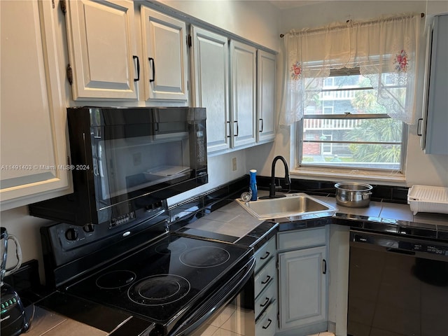 kitchen featuring light tile patterned floors, black appliances, sink, and tile countertops