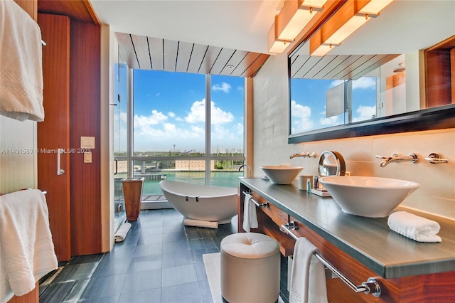 bathroom with dual vanity, a bathing tub, floor to ceiling windows, a water view, and tile flooring