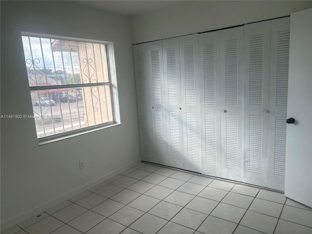 unfurnished bedroom featuring a closet and light tile floors