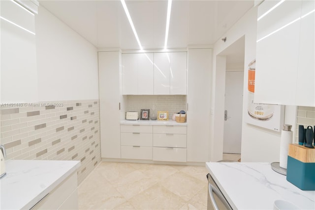 kitchen featuring white cabinets, light tile flooring, tasteful backsplash, and light stone counters