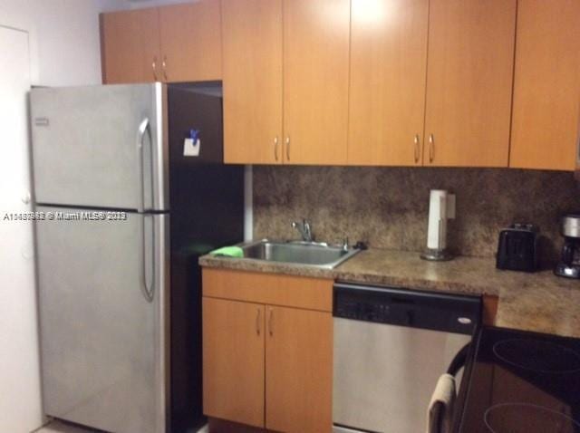 kitchen featuring light stone counters, backsplash, stainless steel appliances, and sink