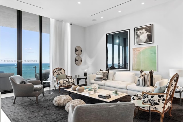 living room featuring floor to ceiling windows, a healthy amount of sunlight, and a water view