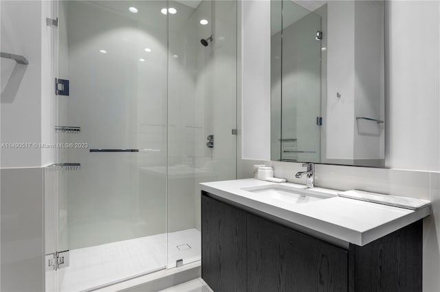 bathroom with a shower with shower door and vanity