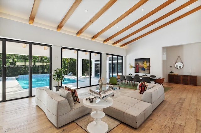 living room with high vaulted ceiling, light hardwood / wood-style floors, and beamed ceiling