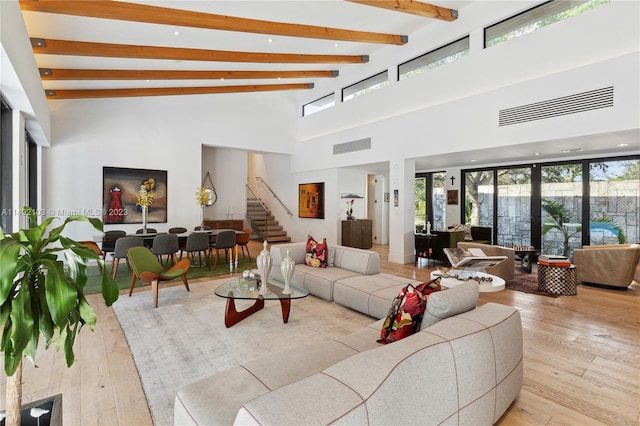 living room with high vaulted ceiling, light hardwood / wood-style flooring, beam ceiling, and a wealth of natural light