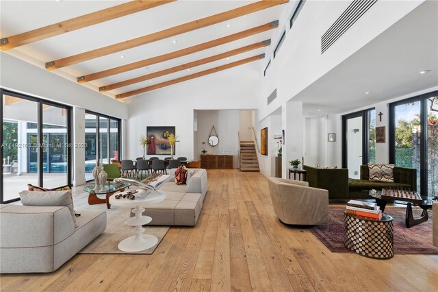 living room featuring beam ceiling, high vaulted ceiling, french doors, and light hardwood / wood-style flooring