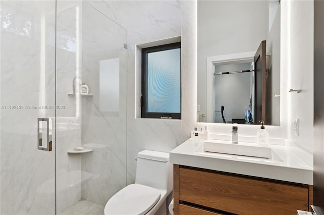 bathroom with vanity, a shower with shower door, toilet, and tile walls