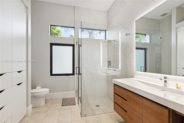 bathroom with toilet, tile floors, vanity, and a wealth of natural light