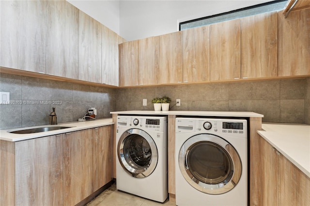 laundry area featuring independent washer and dryer, light tile floors, cabinets, and sink