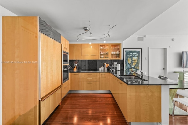 kitchen with built in appliances, sink, dark wood-type flooring, kitchen peninsula, and decorative backsplash