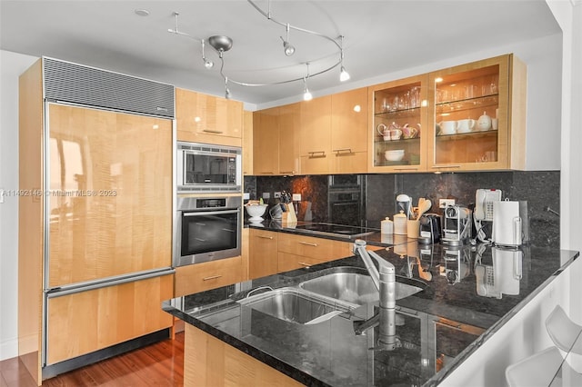 kitchen featuring built in appliances, dark hardwood / wood-style flooring, dark stone countertops, and backsplash