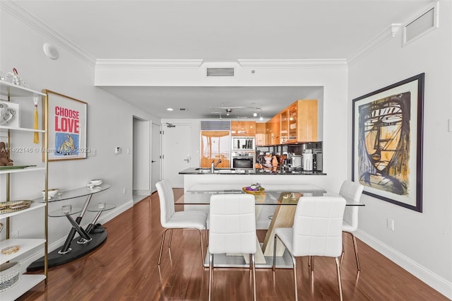 dining room featuring sink, ornamental molding, and dark wood-type flooring