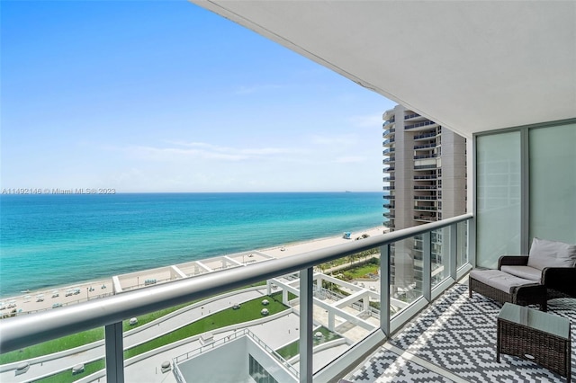 balcony with a water view and a view of the beach