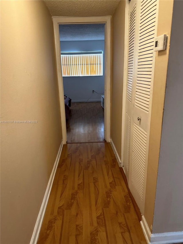 hall with light hardwood / wood-style floors and a textured ceiling