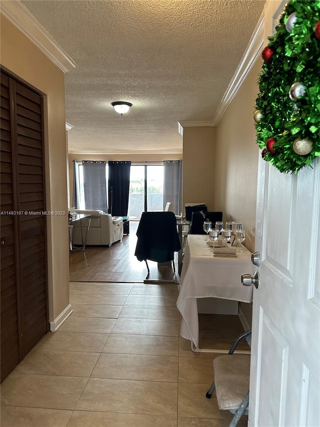 interior space with light tile patterned floors, a textured ceiling, and ornamental molding