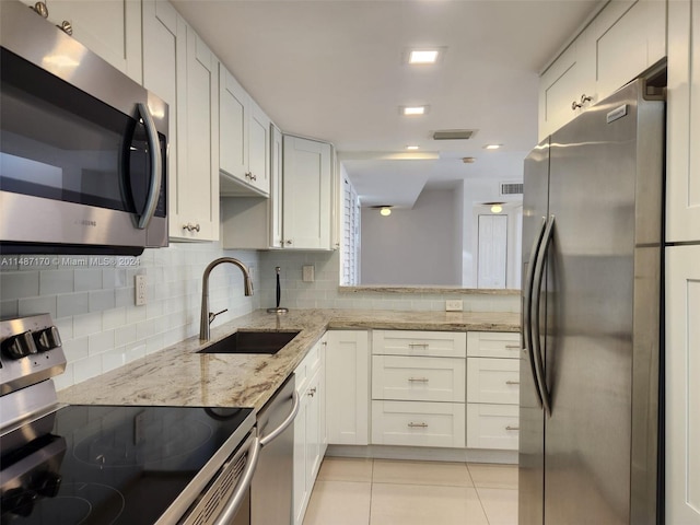 kitchen featuring sink, light tile floors, appliances with stainless steel finishes, light stone countertops, and tasteful backsplash