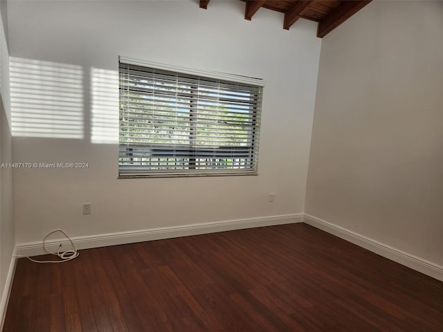 empty room featuring vaulted ceiling with beams, wooden ceiling, and dark wood-type flooring