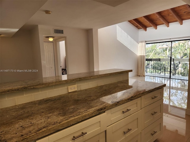 kitchen featuring light tile floors, white cabinets, beam ceiling, light stone counters, and wood ceiling