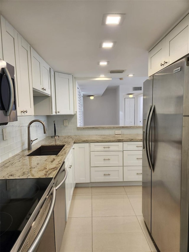 kitchen featuring stainless steel appliances, tasteful backsplash, white cabinetry, sink, and light stone counters