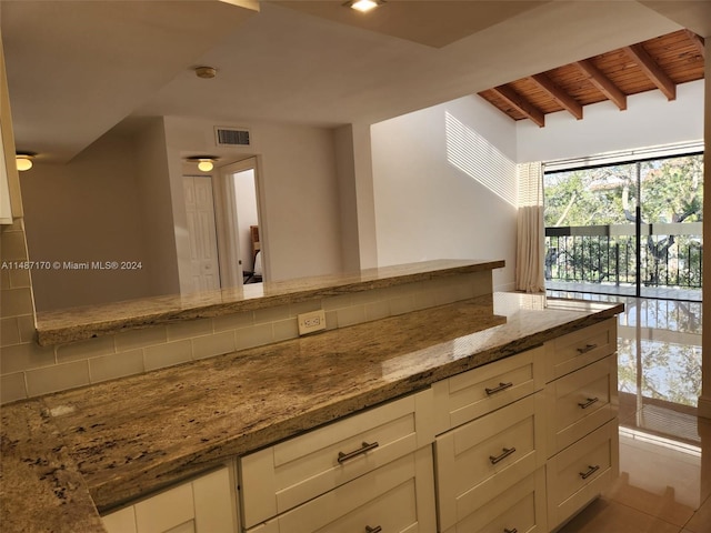 kitchen featuring light stone counters, white cabinets, beam ceiling, wooden ceiling, and tasteful backsplash