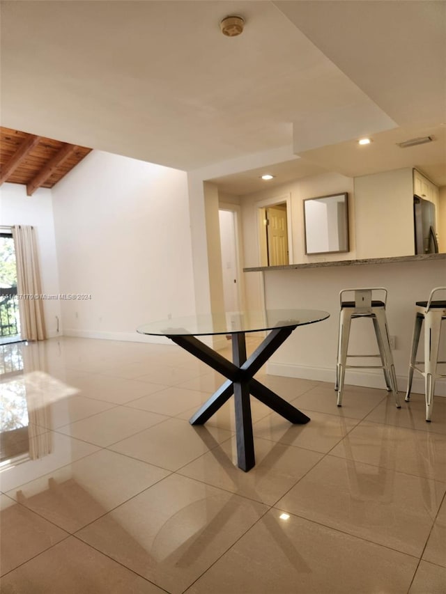 unfurnished dining area with beam ceiling and light tile floors