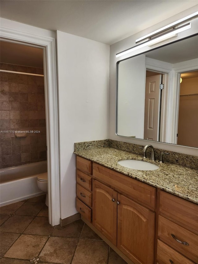 full bathroom with tile floors, large vanity, toilet, and tiled shower / bath