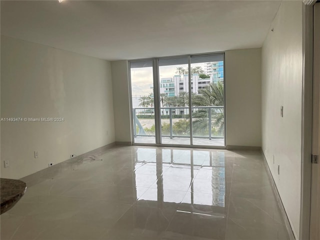 empty room featuring floor to ceiling windows and light tile flooring