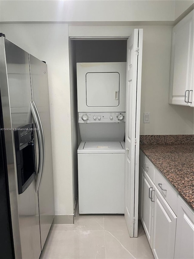 laundry room with stacked washer and dryer and light tile flooring