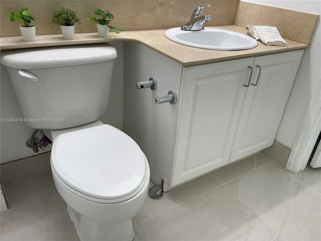 bathroom featuring toilet, vanity, and tile flooring