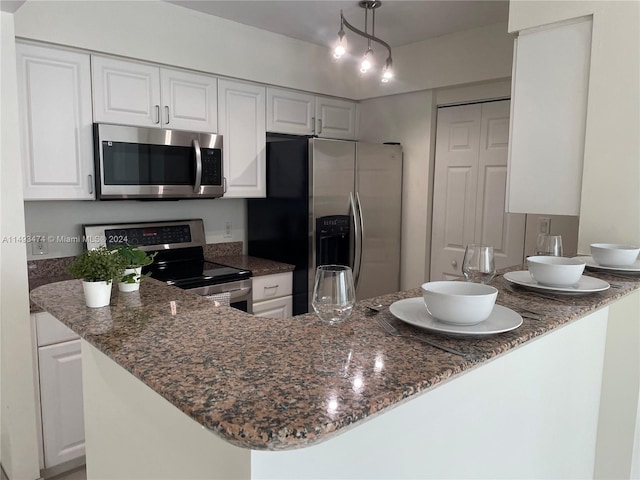 kitchen with white cabinets, track lighting, stainless steel appliances, and dark stone counters