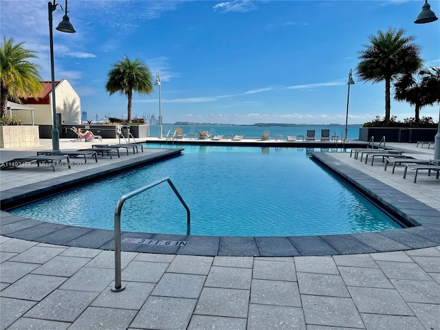 view of pool with a patio area and a water view