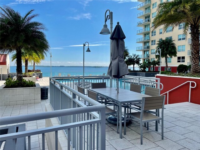 view of patio / terrace featuring central AC unit, a water view, and a balcony