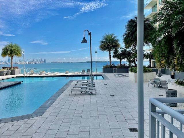 view of pool featuring a water view and a patio area