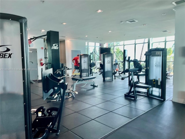 gym with a wall of windows and dark tile floors