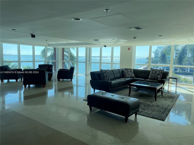 living room featuring light tile flooring, a water view, and expansive windows