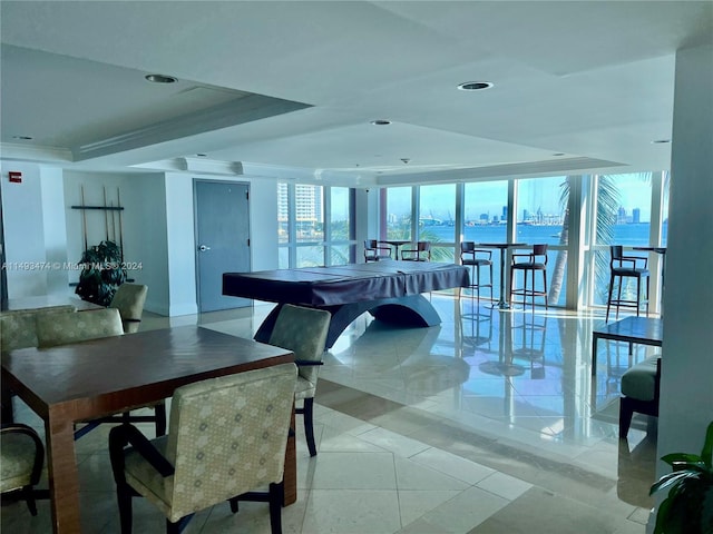 tiled dining space featuring a water view, a tray ceiling, and expansive windows