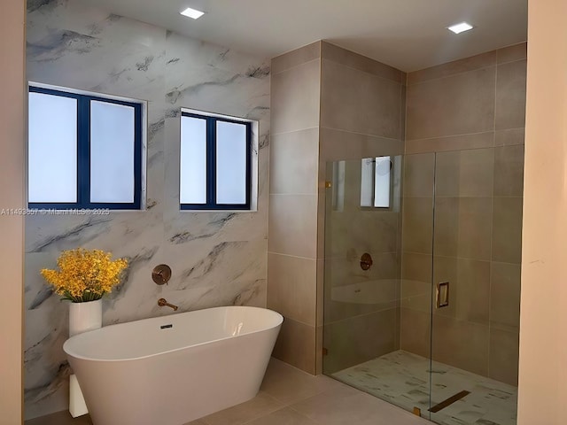 full bath with tile patterned floors, a soaking tub, a shower stall, and tile walls