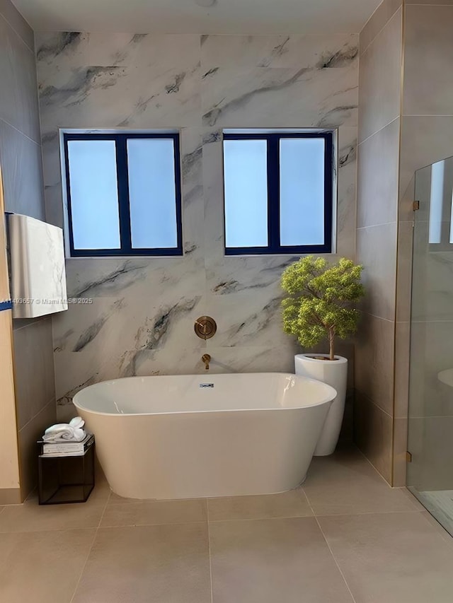 full bath with tile patterned flooring, a shower stall, a wealth of natural light, and a freestanding bath