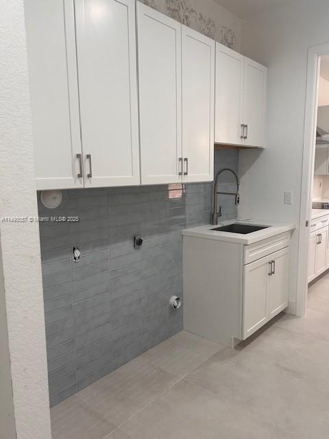 laundry area featuring light tile patterned floors, laundry area, and a sink