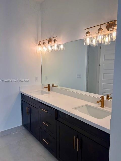 bathroom with a sink, baseboards, double vanity, and tile patterned floors