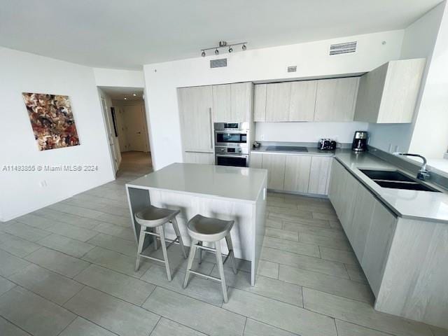 kitchen with sink, stainless steel double oven, a breakfast bar area, light tile flooring, and stovetop